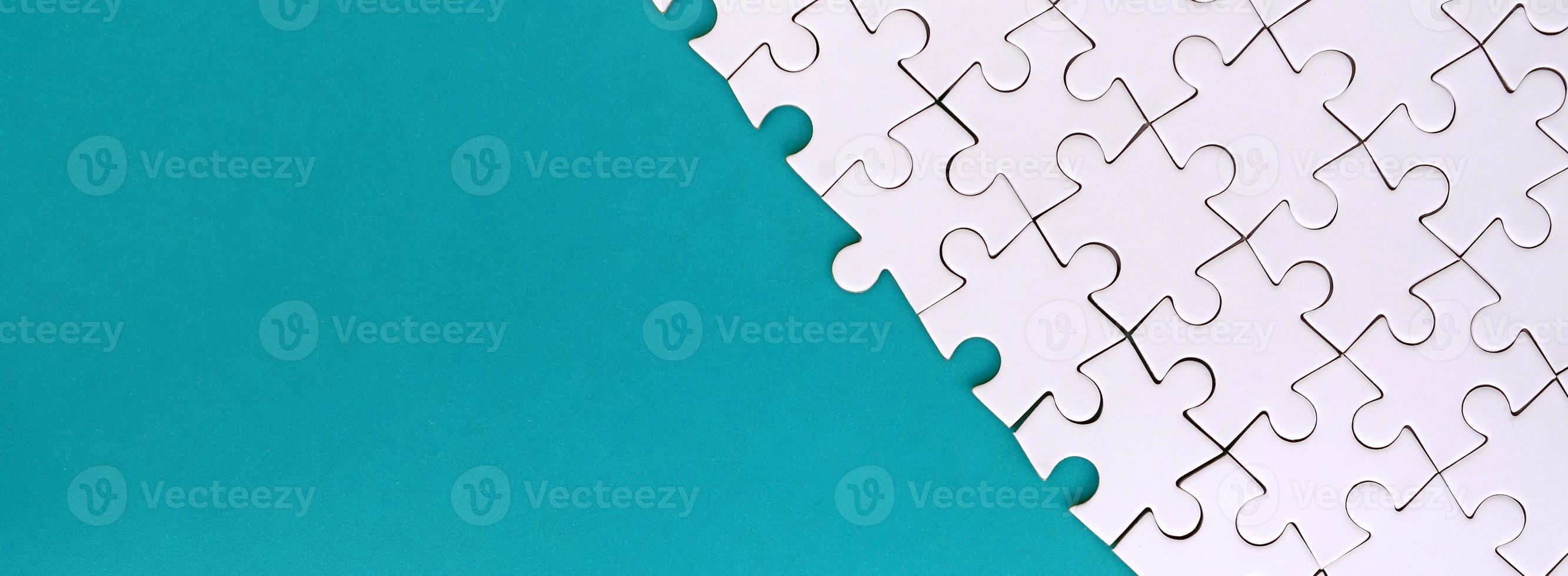 Fragment of a folded white jigsaw puzzle on the background of a blue plastic surface. Texture photo with copy space for text