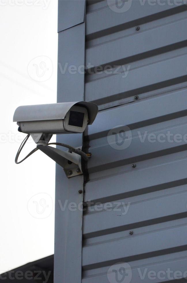 White surveillance camera built into the metal wall of the office building photo