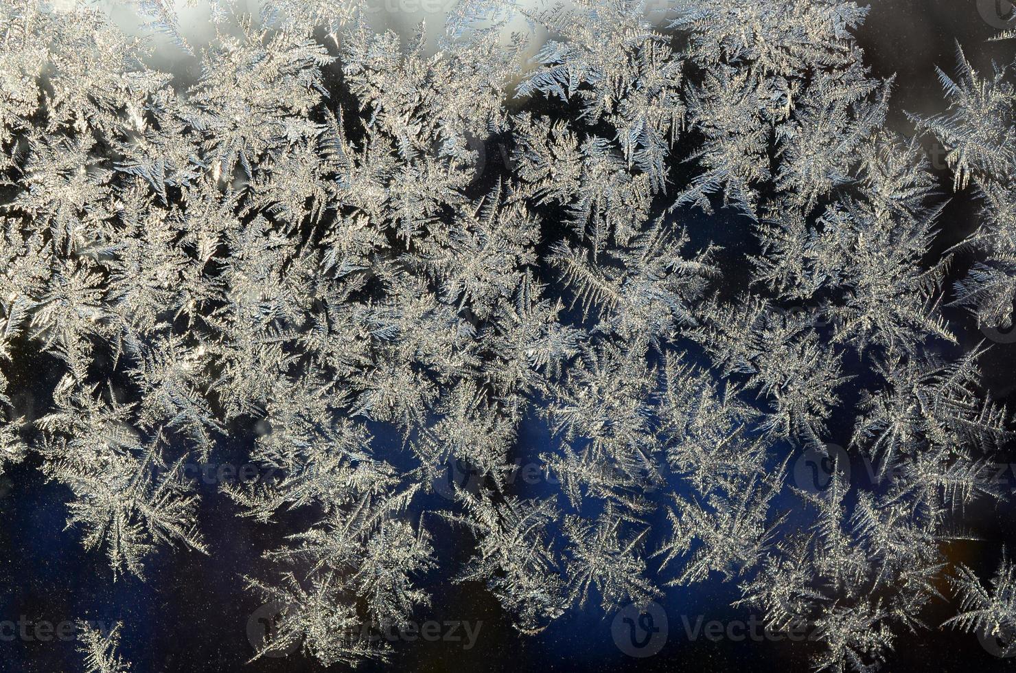 Snowflakes frost rime macro on window glass pane photo