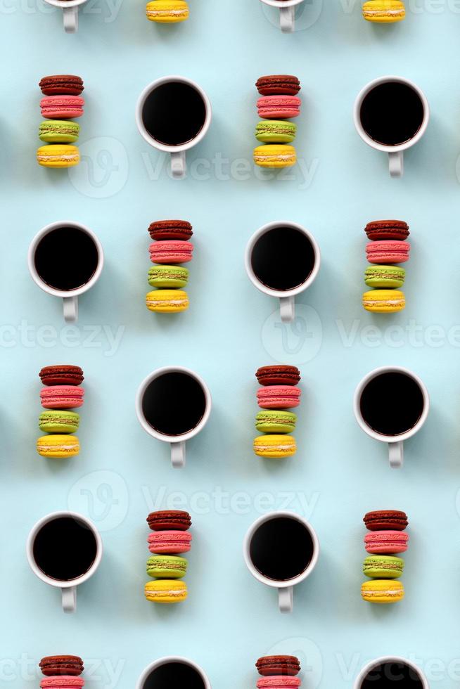 un patrón de muchos coloridos macarrones de pastel de postre y tazas de café en la moderna vista superior de fondo azul pastel. composición plana foto