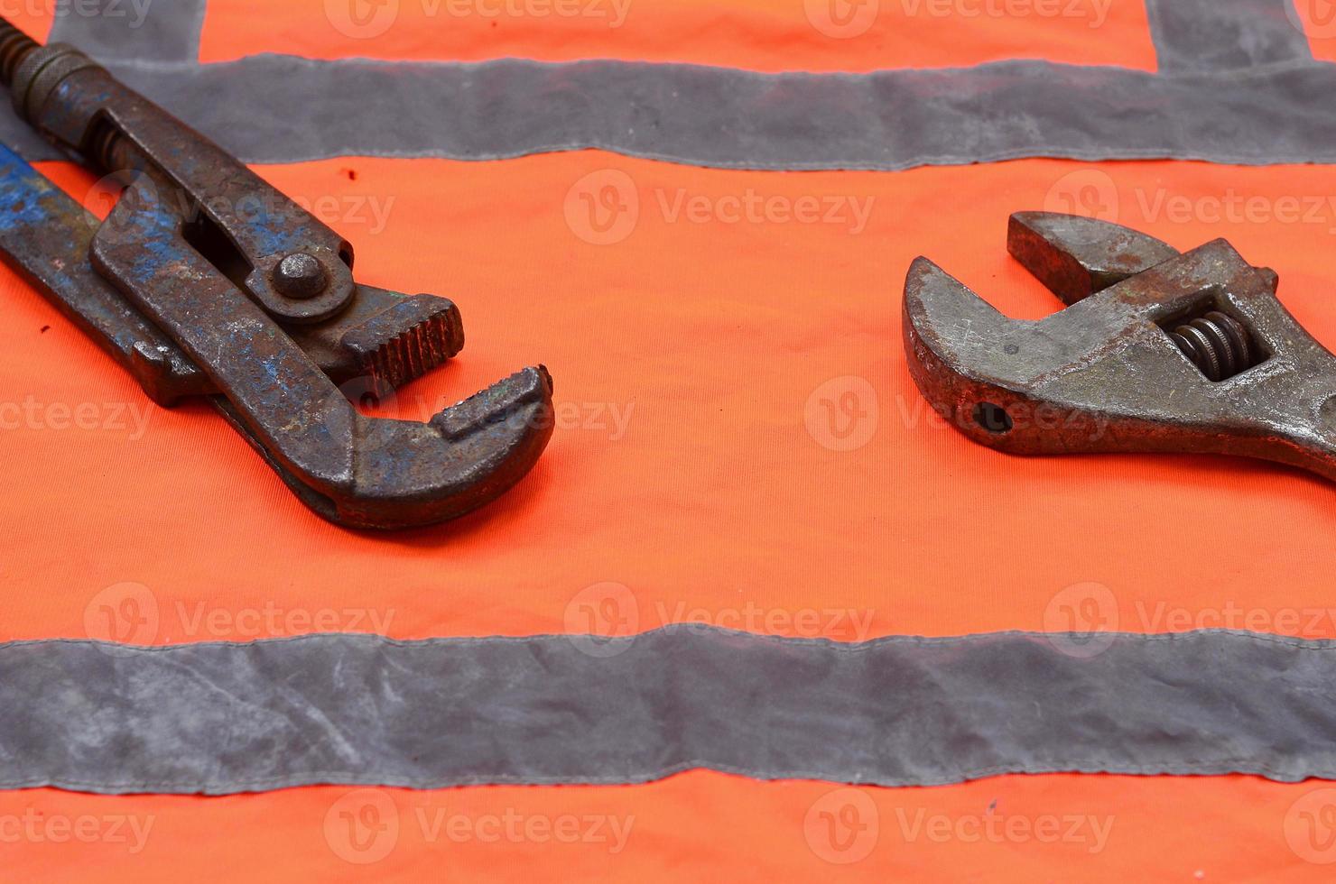 Adjustable and pipe wrenches against the background of an orange photo