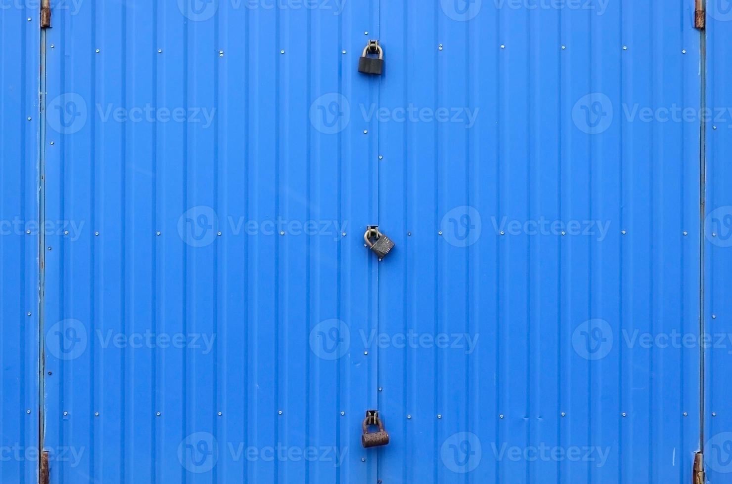Texture of a metal blue wall with a gate closed for three locks photo