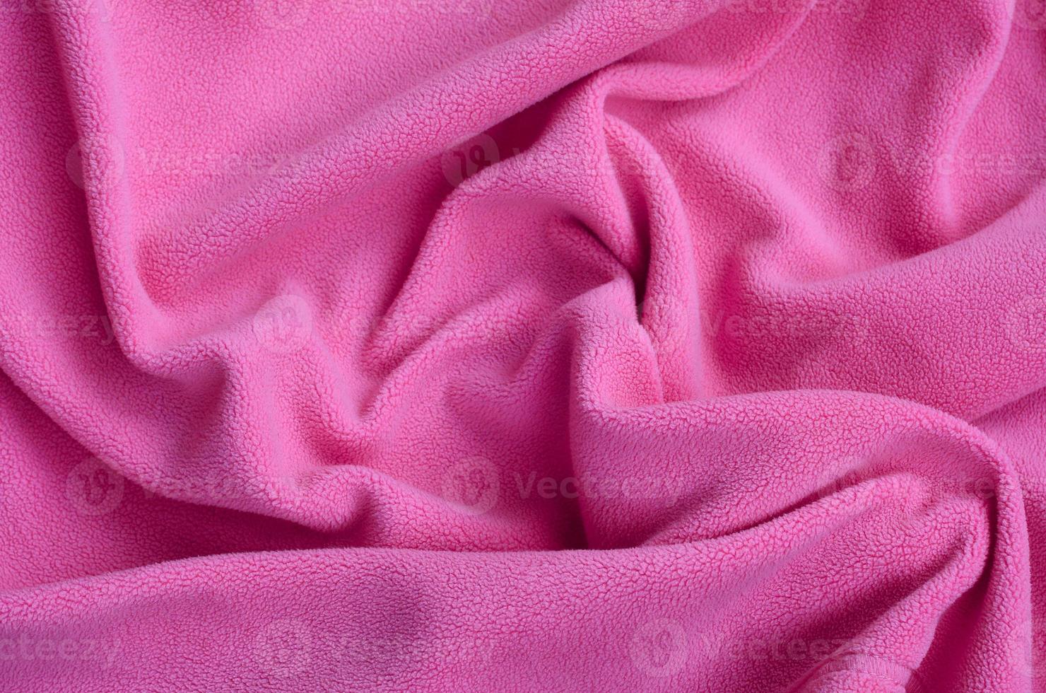 The blanket of furry pink fleece fabric. A background of light pink soft plush fleece material with a lot of relief folds photo