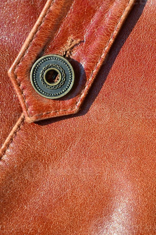 Brown leather texture. Useful as background for any design work. Macro photo of a button on outer clothing made of genuine leather