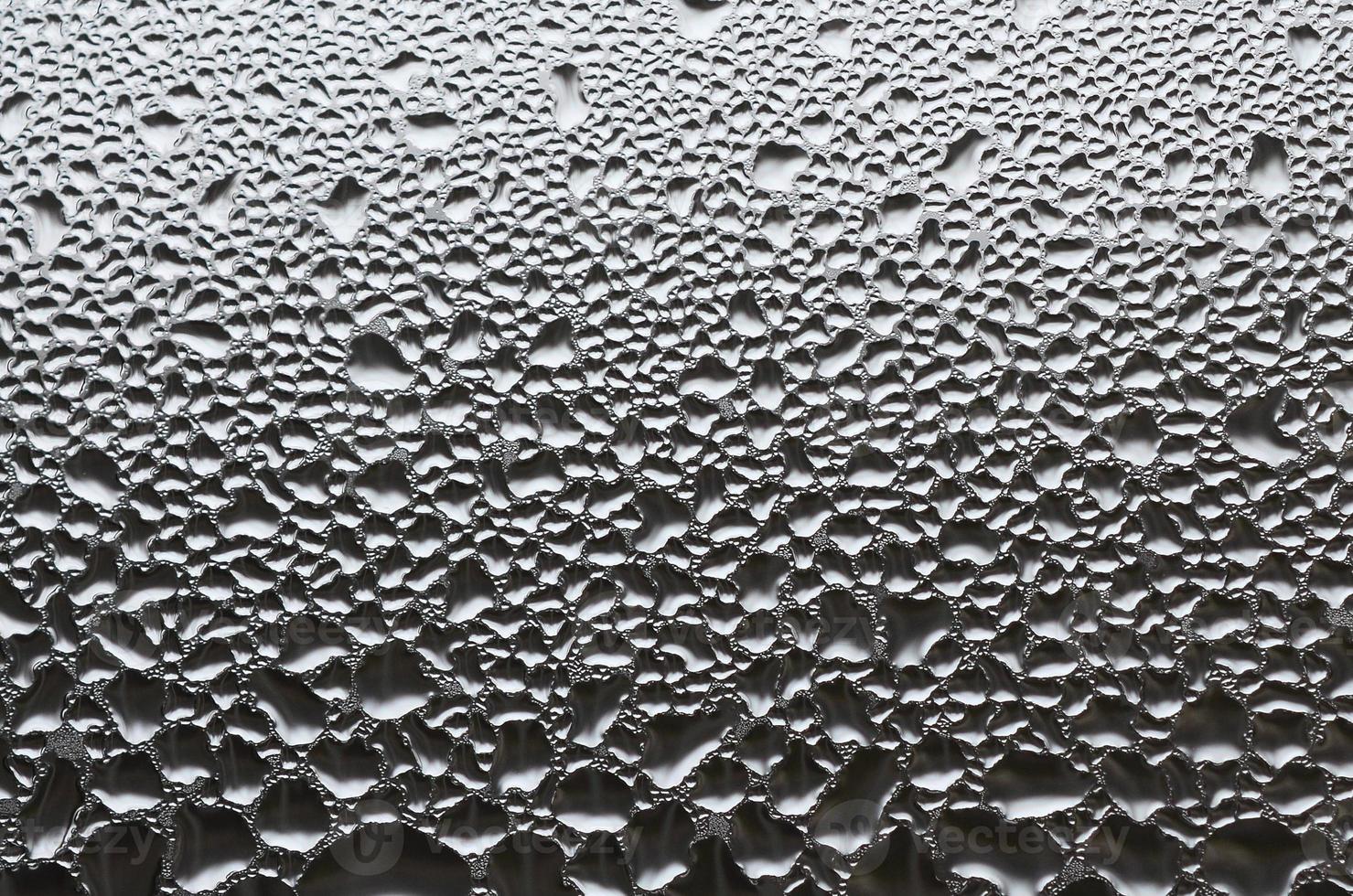 A photo of the glass surface of the window, covered with a multitude of droplets of various sizes. Background texture of a dense layer of condensate on glass