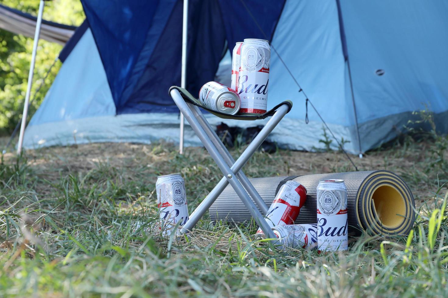 SUMY, UKRAINE - AUGUST 01, 2021 Few Cans of Budweiser Lager Alcohol Beer on fisherman chair outdoors. Budweiser is a Brand from Anheuser-Busch Inbev photo