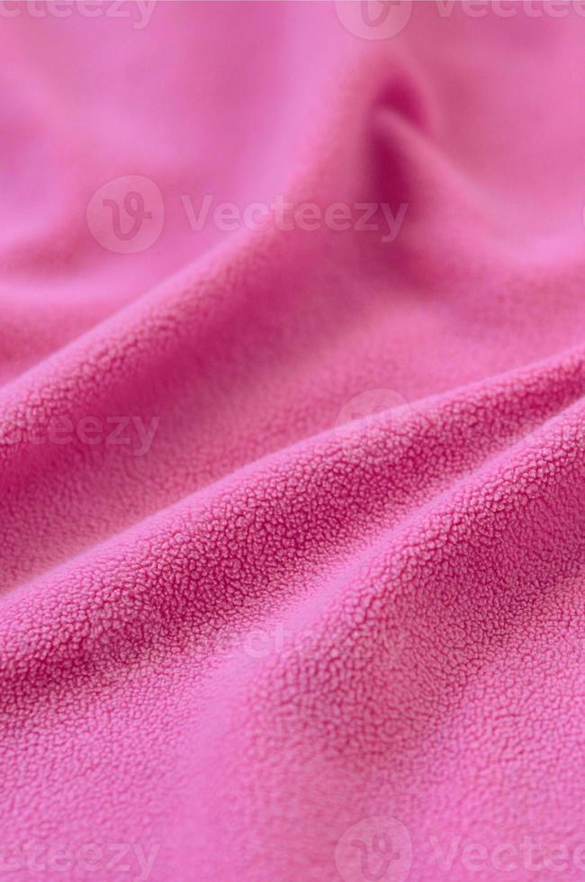 The blanket of furry pink fleece fabric. A background of light pink soft plush fleece material with a lot of relief folds photo
