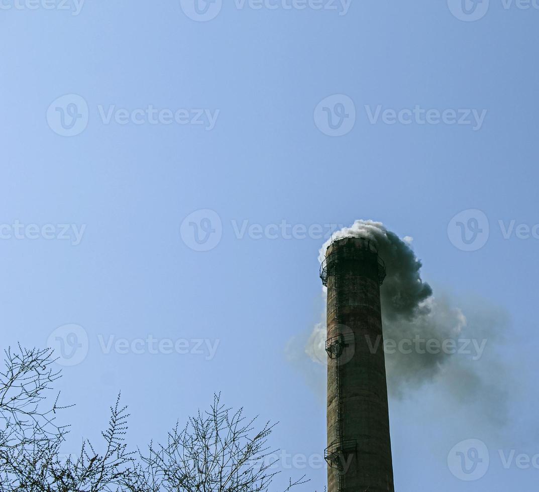 Smoke from the chimney of a chemical plant against the blue sky. The problem of environmental pollution. Ecology concept photo