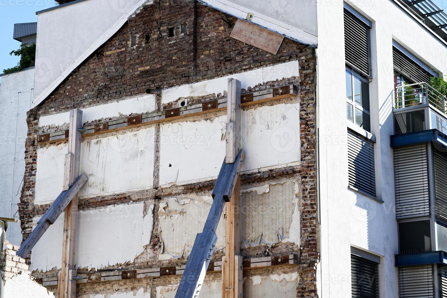 Support of a building wall with wooden struts after demolition of an old building photo
