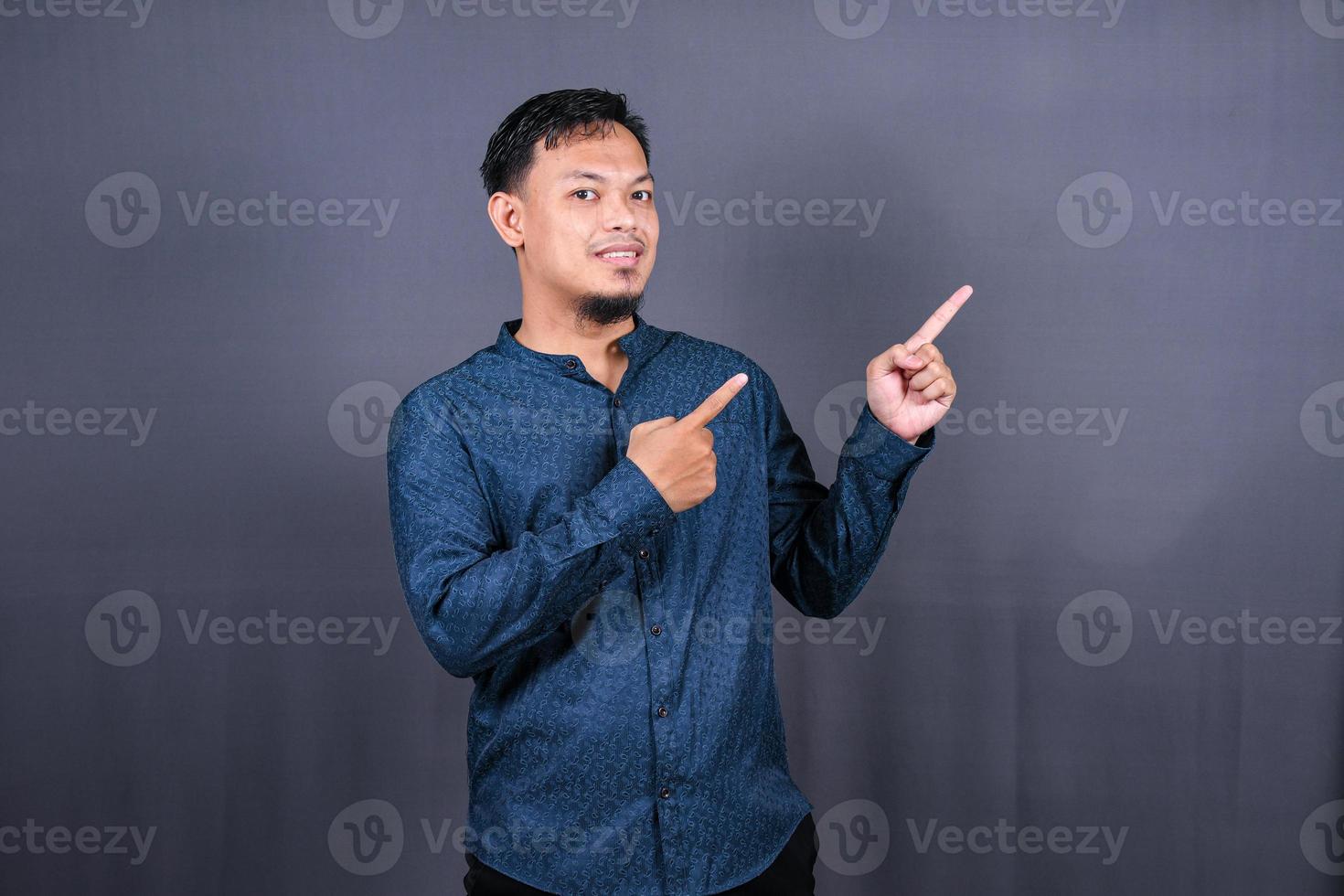 Young asian man isolated on gray background pointing to the side to present a product photo