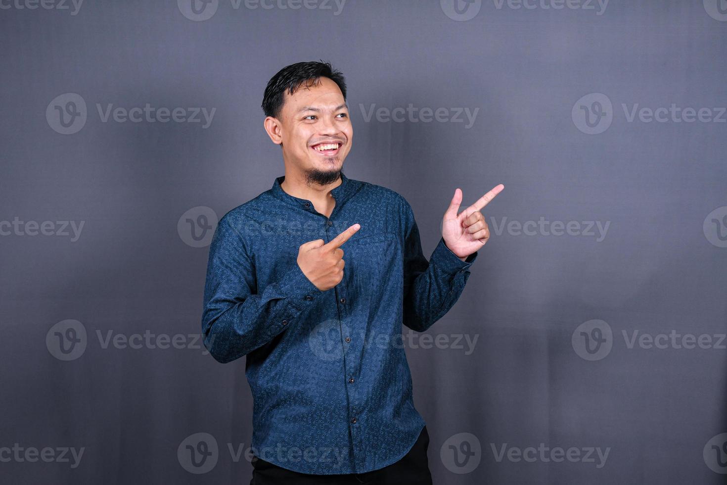 Young asian man isolated on gray background pointing to the side to present a product photo