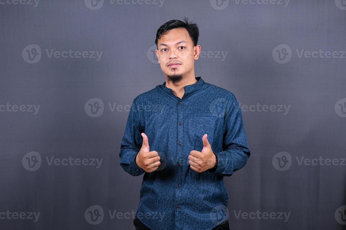 Young handsome asian man over gray background Smiling relaxed and cheerful Success and optimistic photo