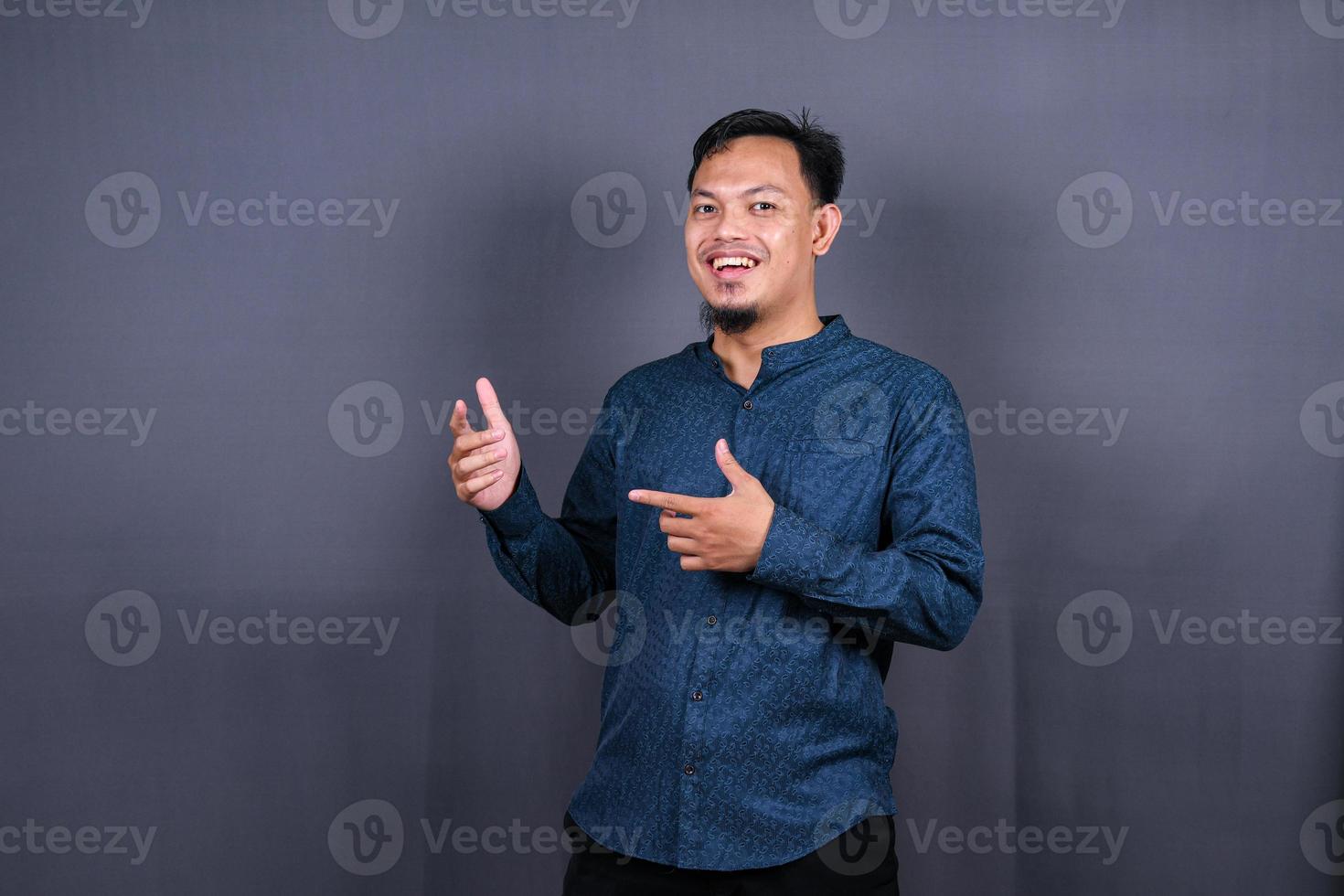 Young asian man isolated on gray background pointing to the side to present a product photo