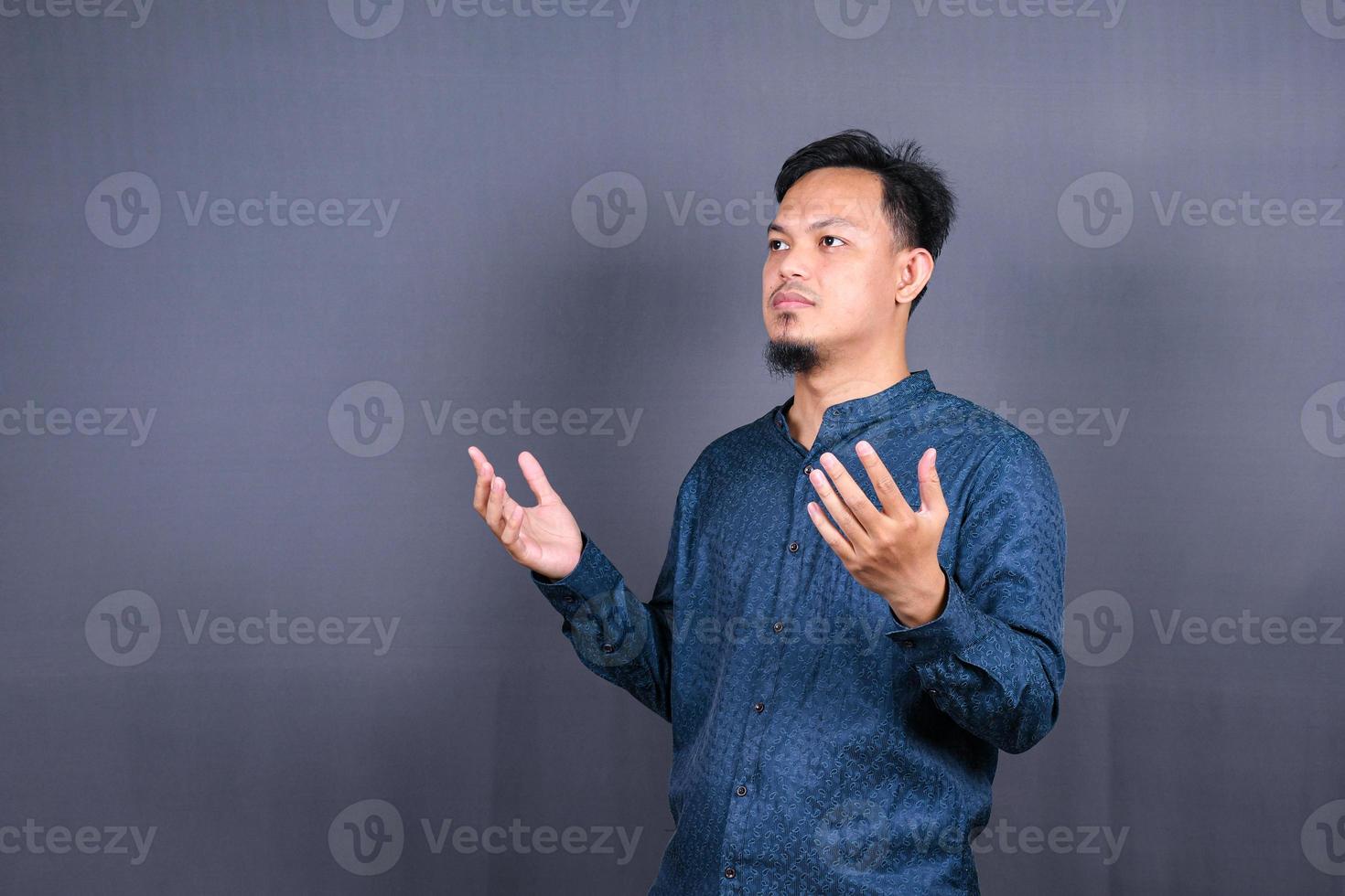 Asian Muslim Man praying to God against on gray background photo