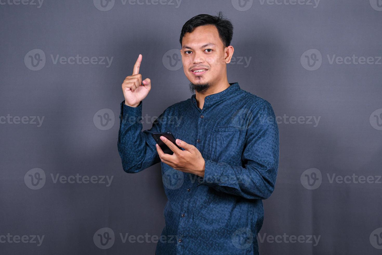 Young asian man isolated on gray background pointing to the side to present a product photo