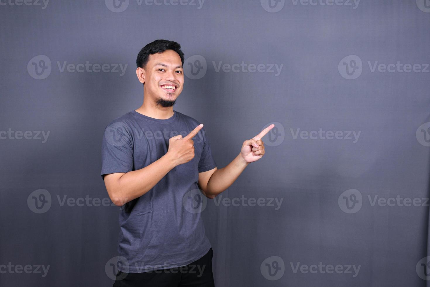 Young attractive smiling asian man in tshirt posing isolated on gray background, Mock up copy space. photo