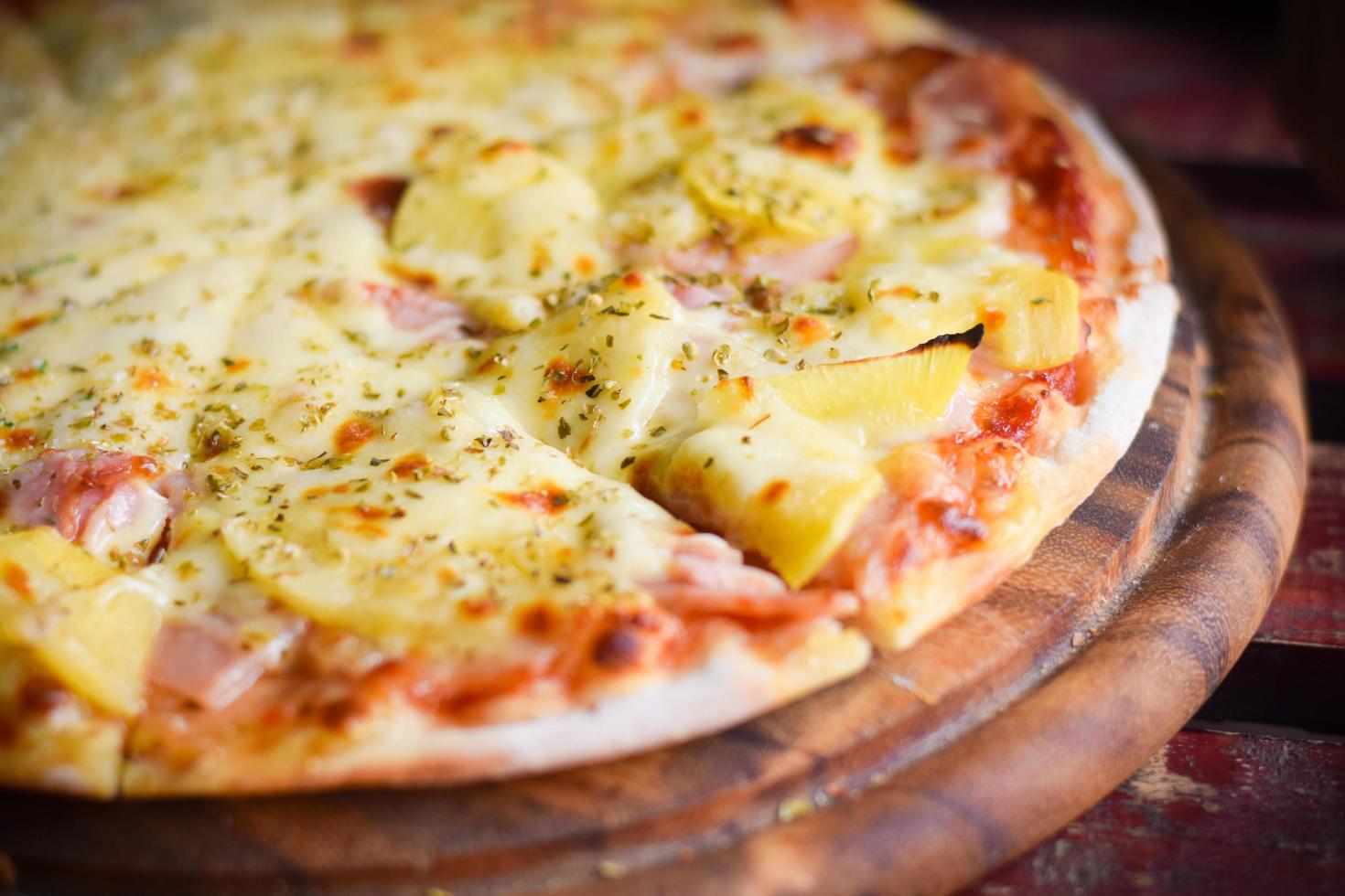 pizza de queso hawaiano sobre mesa de madera. concepto de comida casera foto