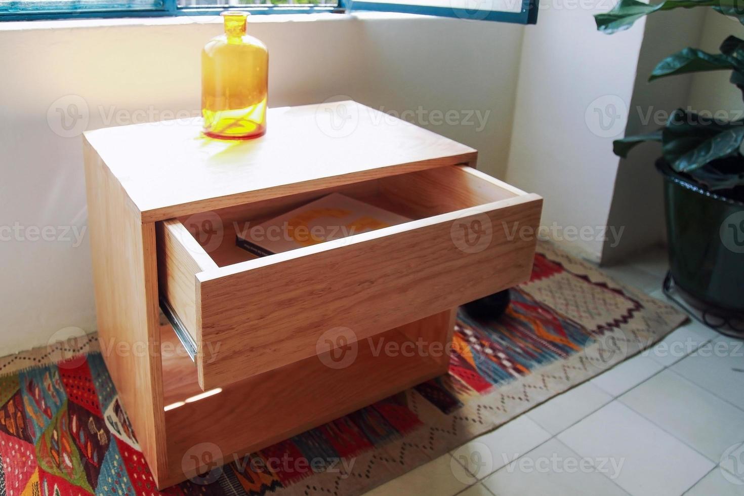 wooden bureau on top of a rug, side table, night table photo