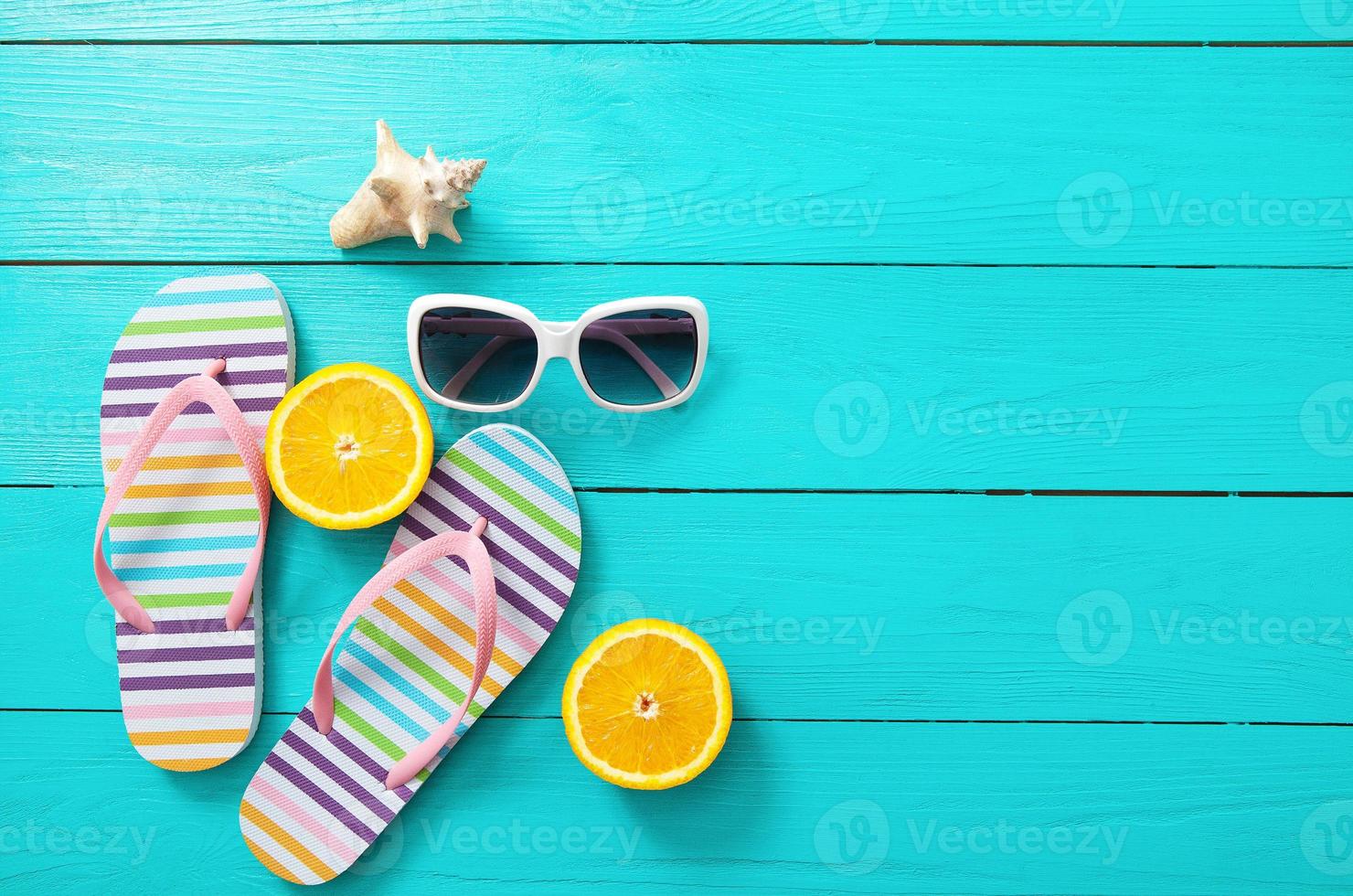 Flip flops, sunglasses and oranges on blue wooden background. Top view and copy space photo