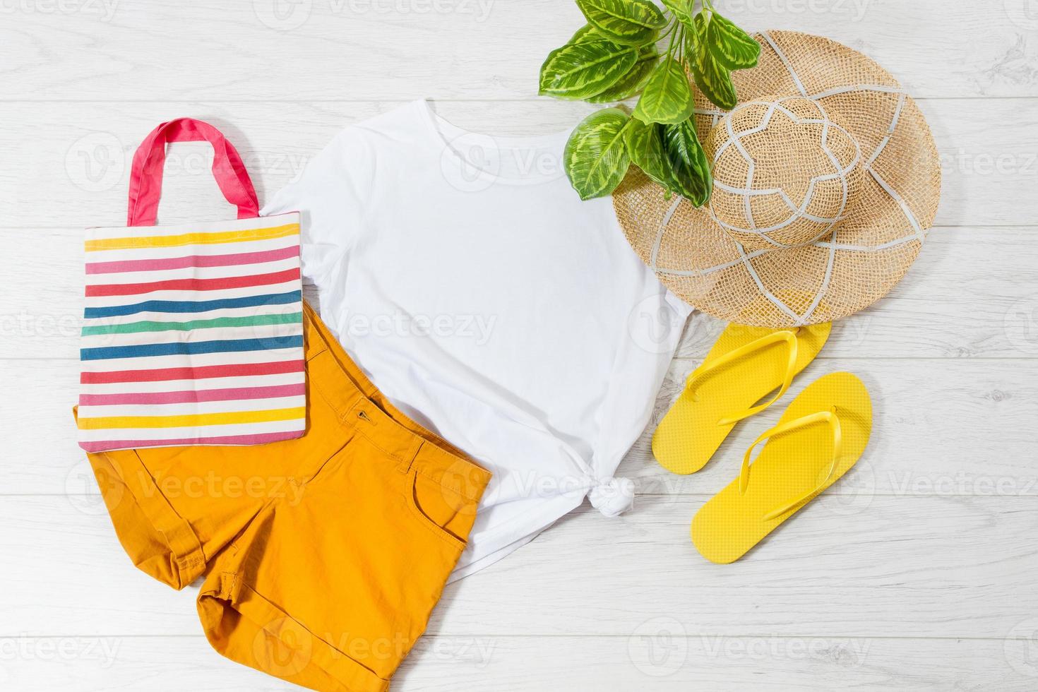 White closeup t shirt mock up flat lay and flip flops on white wooden background. Top view and copy space. Mockup summer t-shirt and summertime. Template blank shirt. photo
