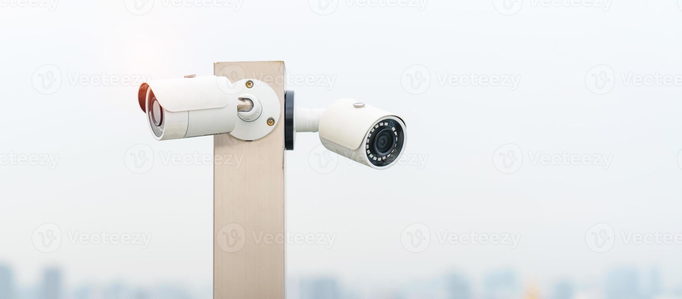 Modern CCTV camera against city and sky background. surveillance, video record and monitoring concept photo