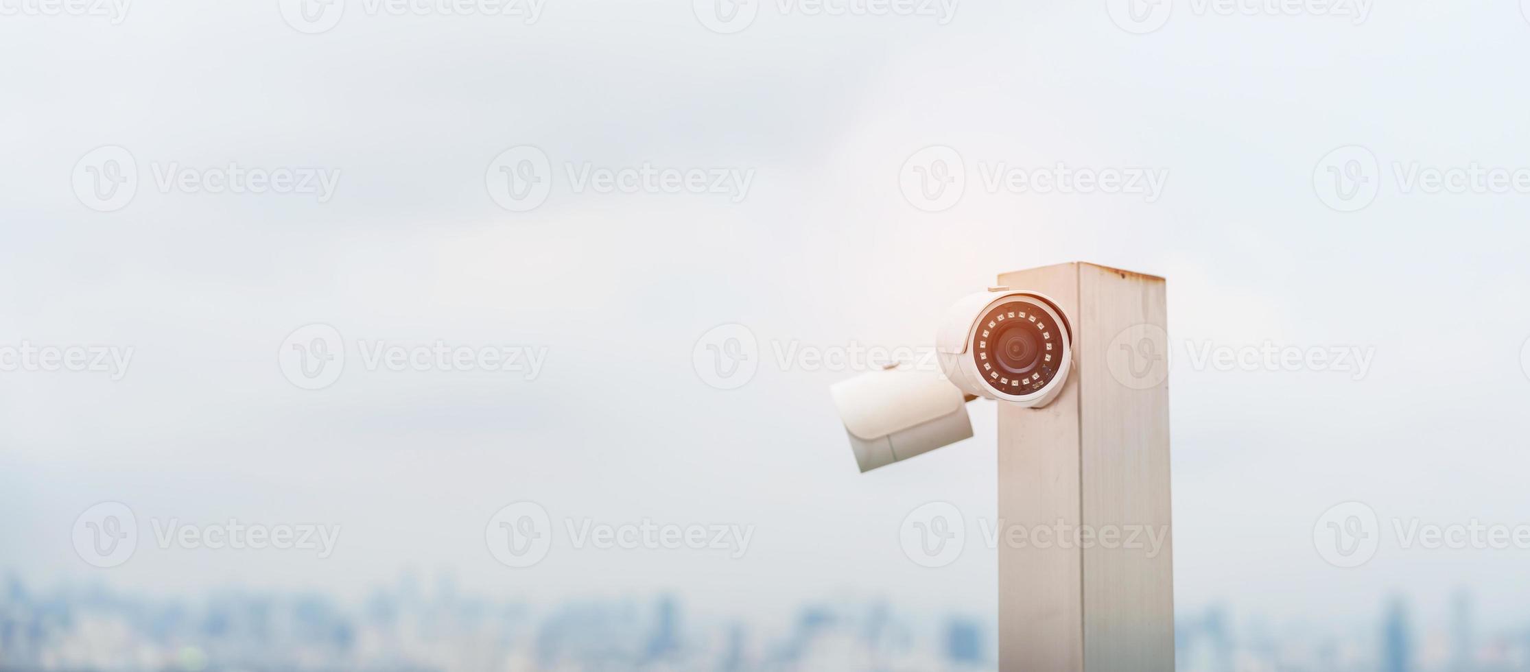 Modern CCTV camera against city and sky background. surveillance, video record and monitoring concept photo