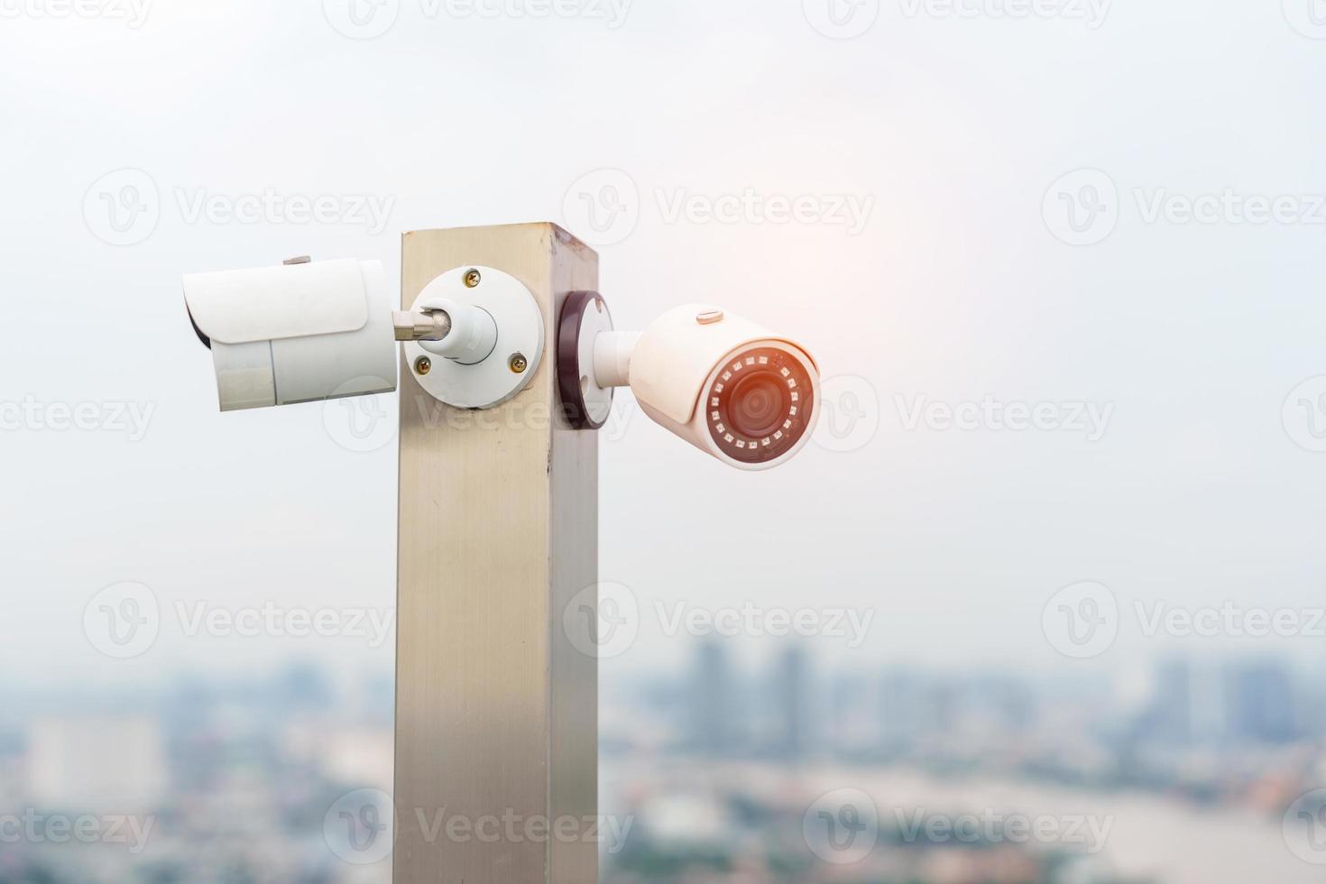 Modern CCTV camera against city and sky background. surveillance, video record and monitoring concept photo