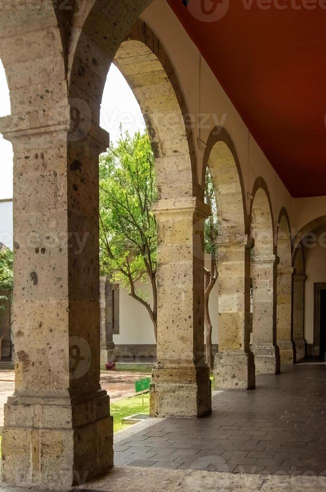 colonial architecture, arches surrounded by vegetation, play of light and shadows inside the space, natural materials photo