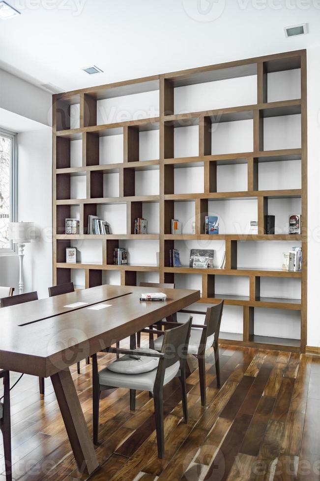 elegante comedor con librería al fondo, tanto la mesa de comedor como la librería de madera natural. foto