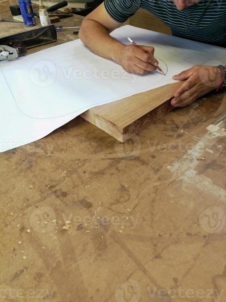 An Anonymous Carpenter Working on New Project at his Workshop. Table top view of unrecognizable man drawing n photo