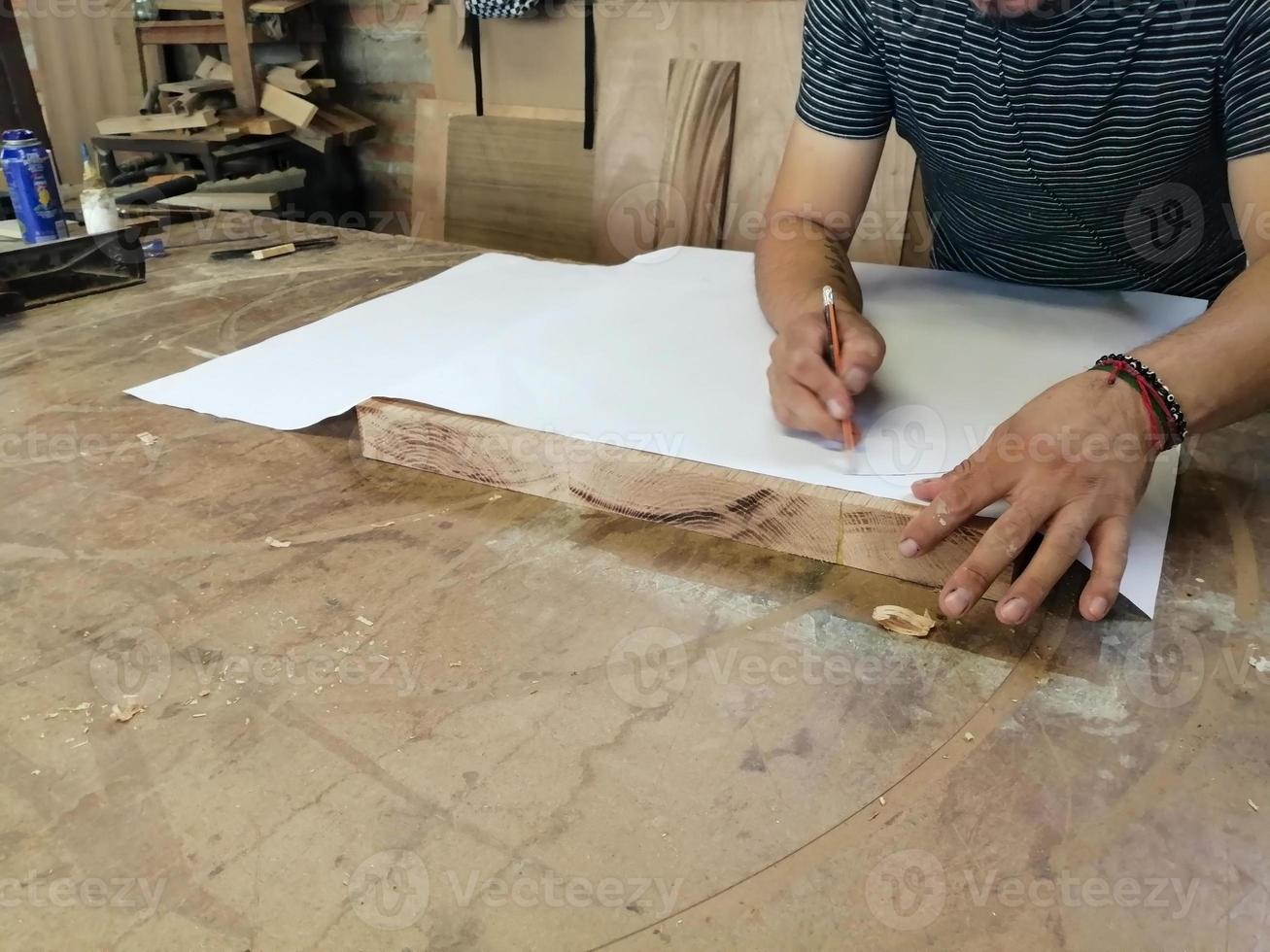 un carpintero anónimo trabajando en un nuevo proyecto en su taller. vista superior de la mesa del hombre irreconocible dibujando n foto