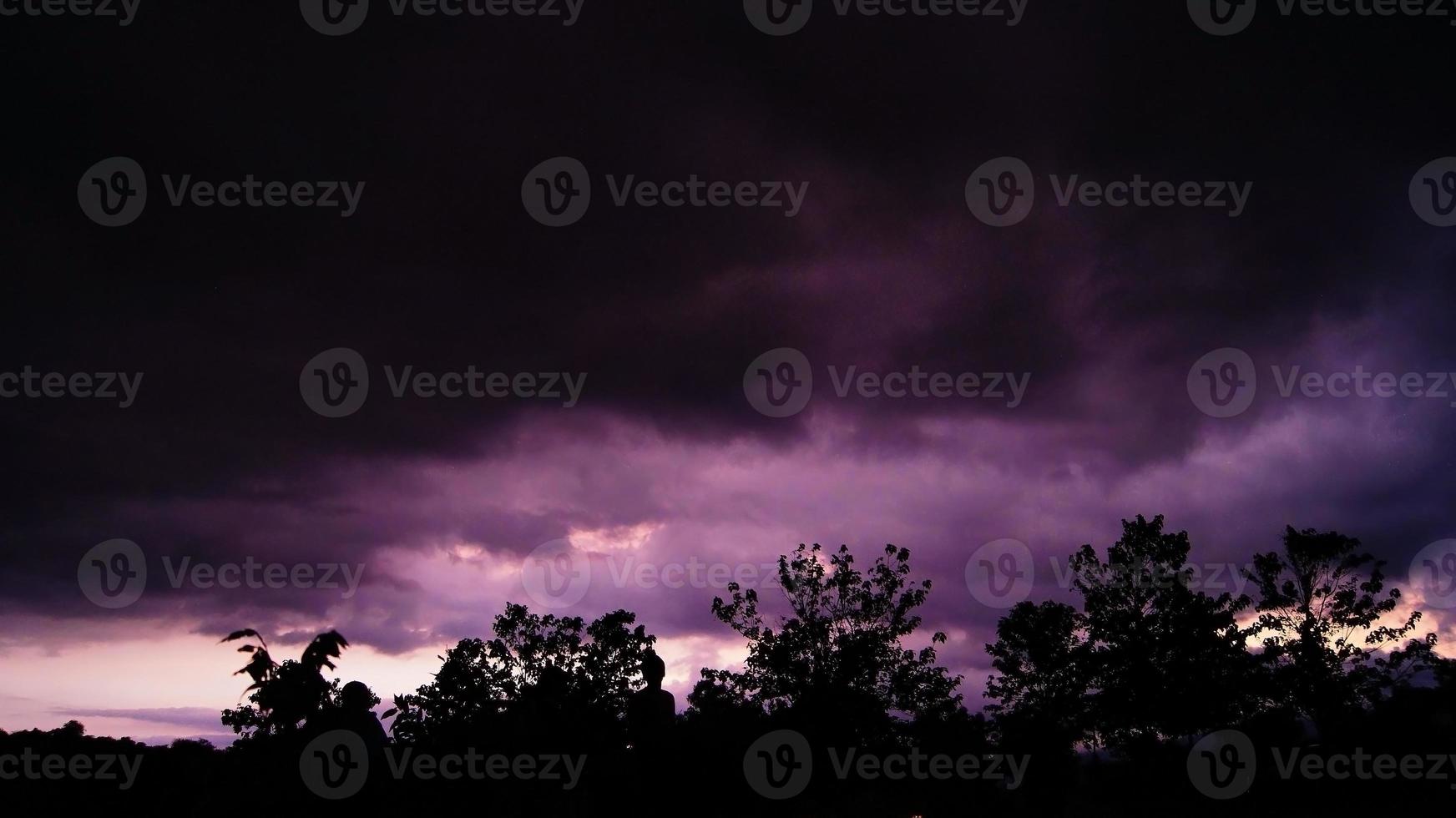 purple sky, cloudy, black silhouette of trees and people looking at the sky photo