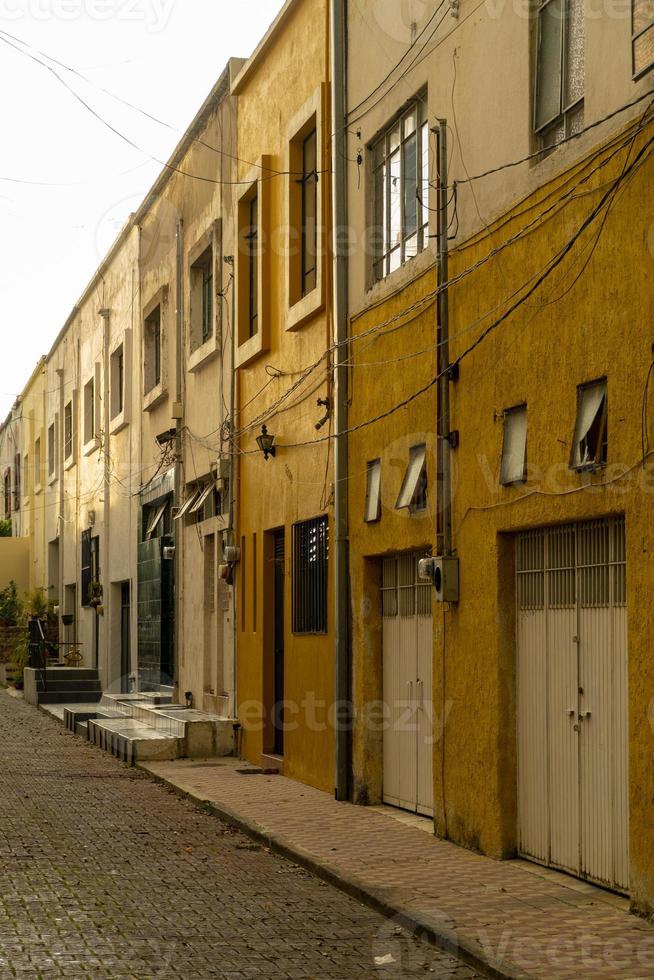 calzada, acera y adoquines en un pequeño barrio, contiguas a casas de color amarillo y mostaza, al atardecer foto