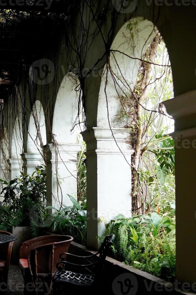 colonial architecture, arches surrounded by vegetation, play of light and shadows inside the space, natural materials photo