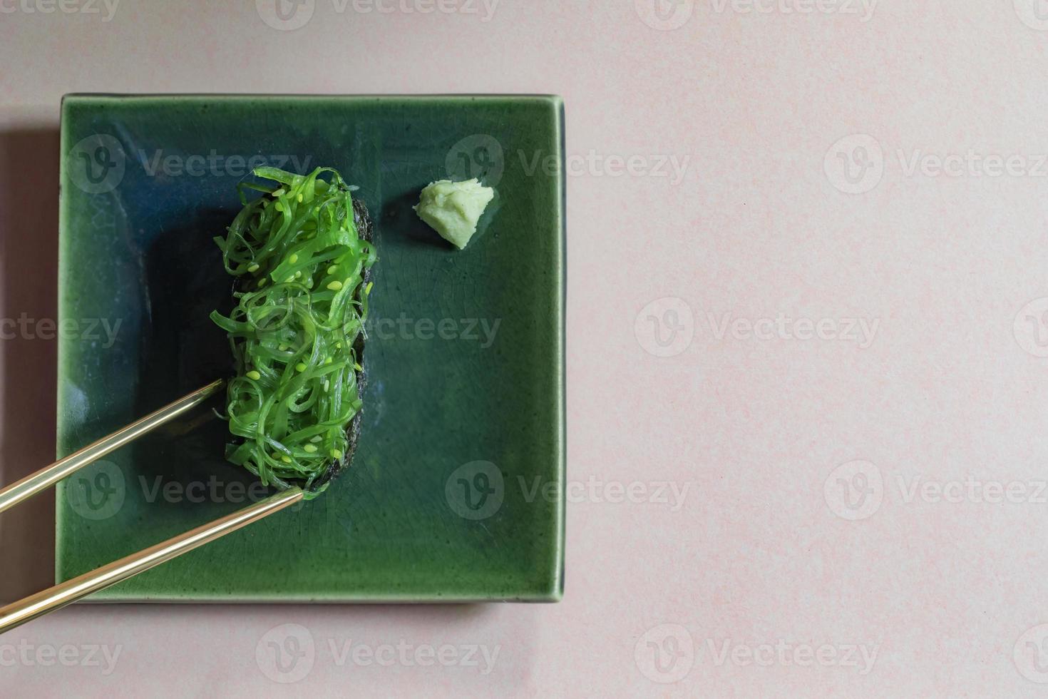 Japanese food seaweed sushi on plate has chopsticks on brown background. photo
