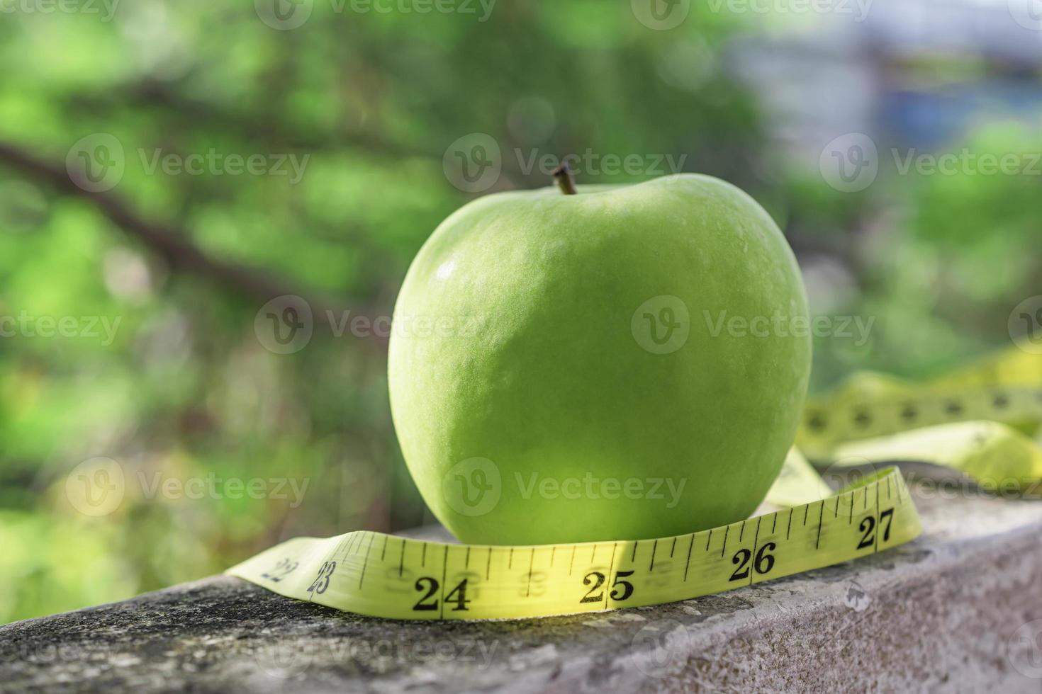 cinta métrica y manzana verde sobre fondo de piedra. foto