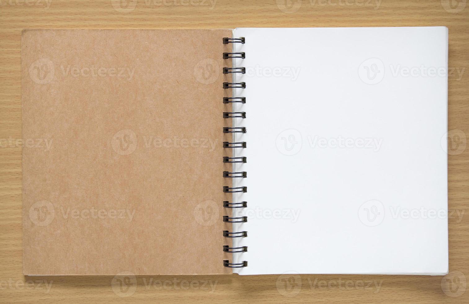 open spiral notebook on wood background photo