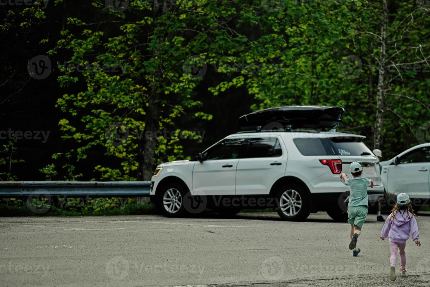 Kids running to car in parking at Austrian alps. photo