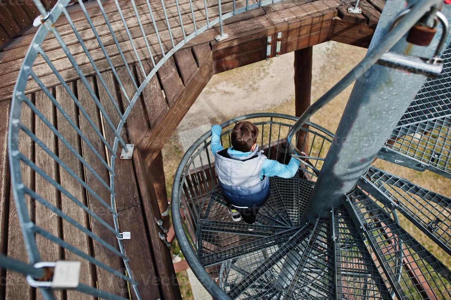 niño camina en la escalera de caracol en la torre de observación de madera. foto