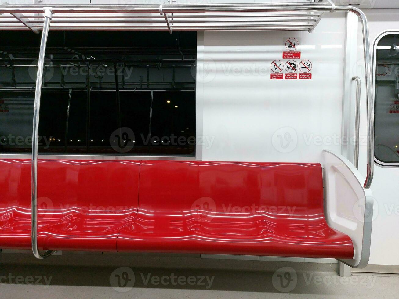 Red row of seats on the train and signs warning No eating or drinking, No Flammable goods, No animals and No smoking in Thai and English. photo