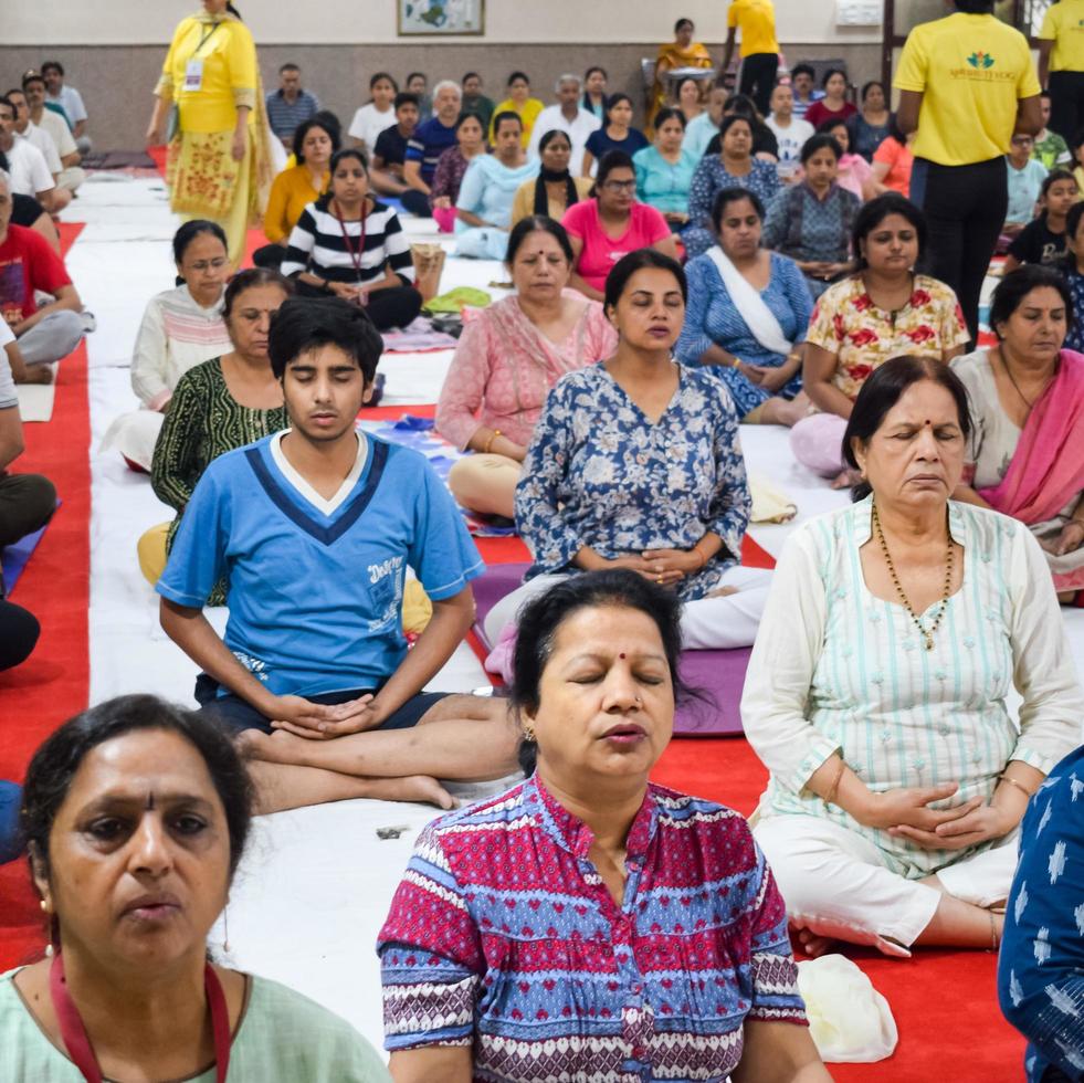 New Delhi, India, June 19 2022 -Group Yoga exercise session for people of different age groups in Balaji Temple, Vivek Vihar, International Yoga Day, Big group of adults attending yoga class in temple photo