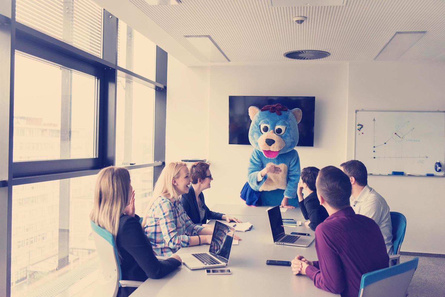 boss dresed as bear having fun with business people in trendy office photo