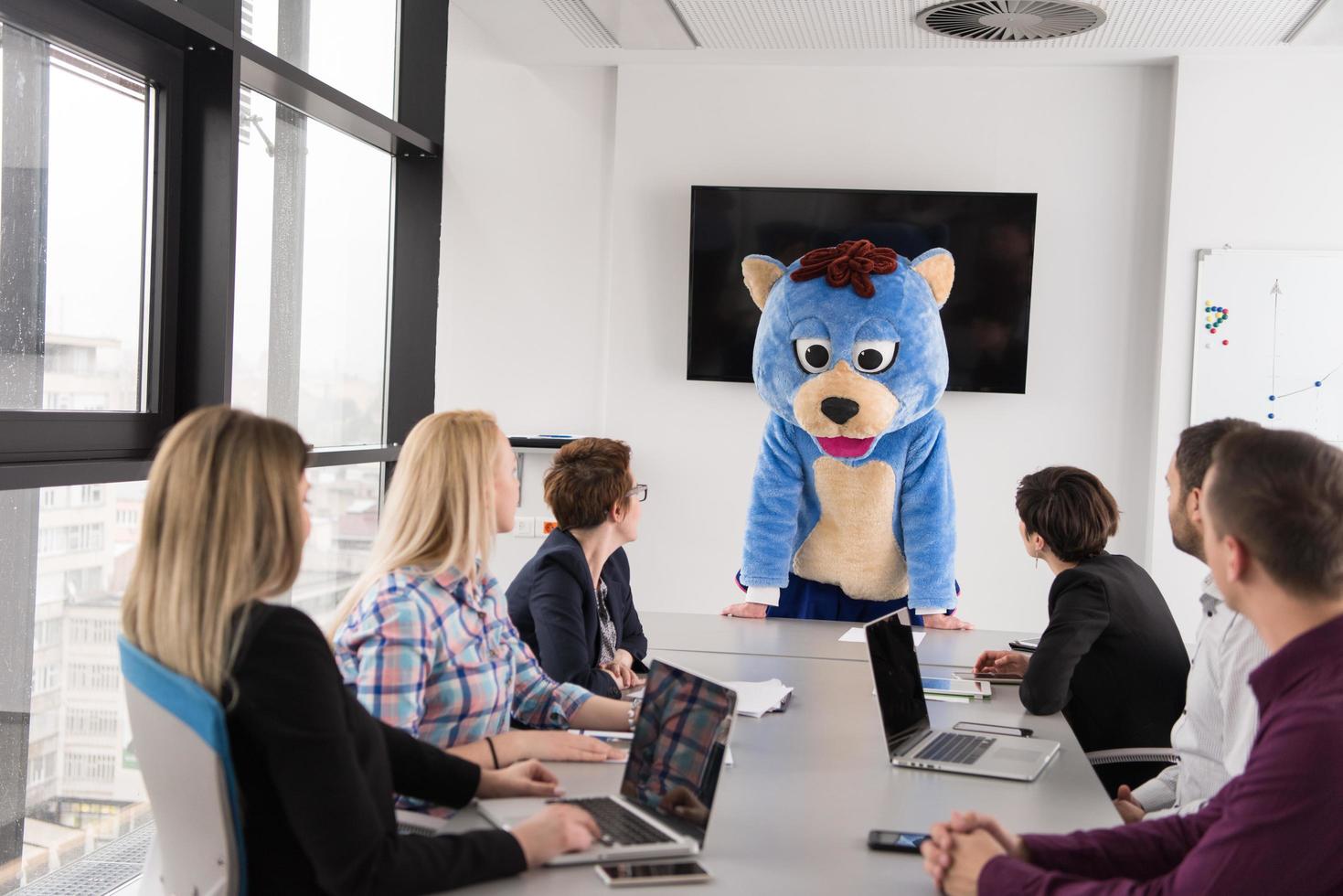 boss dresed as bear having fun with business people in trendy office photo