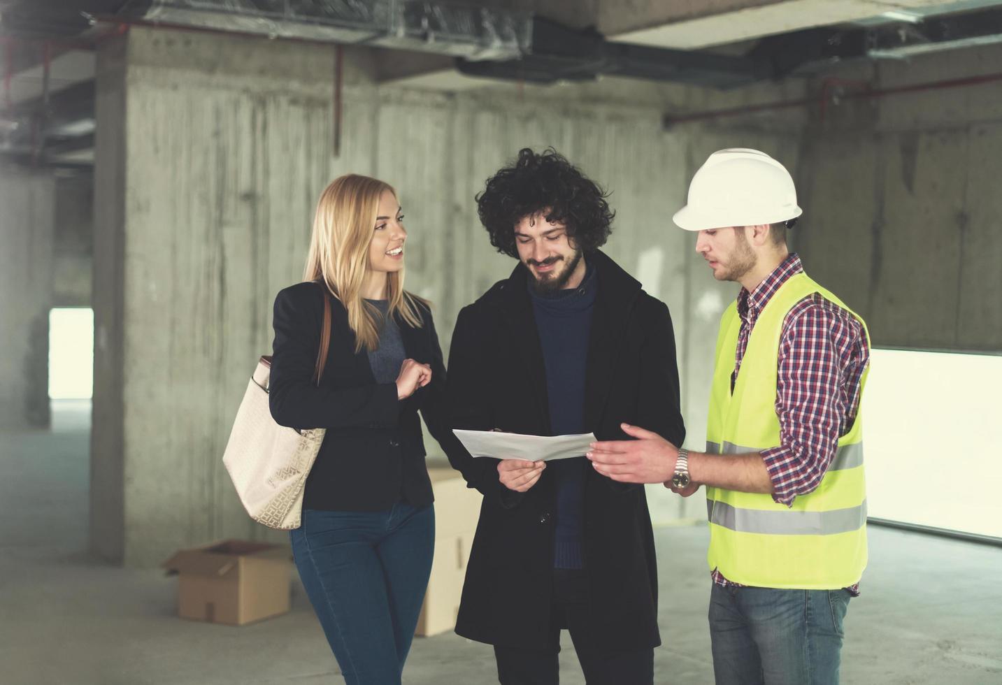 architect showing house design plans to a young couple photo