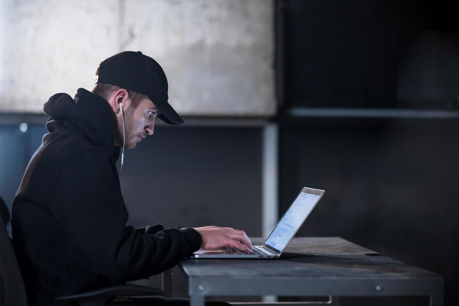 talented hacker using laptop computer while working in dark office photo