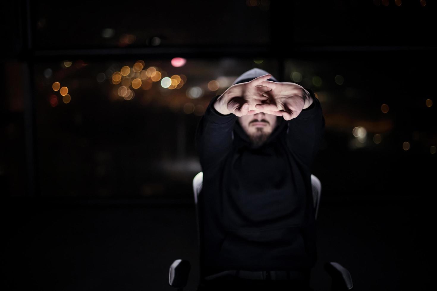 hacker using laptop computer while working in dark office photo