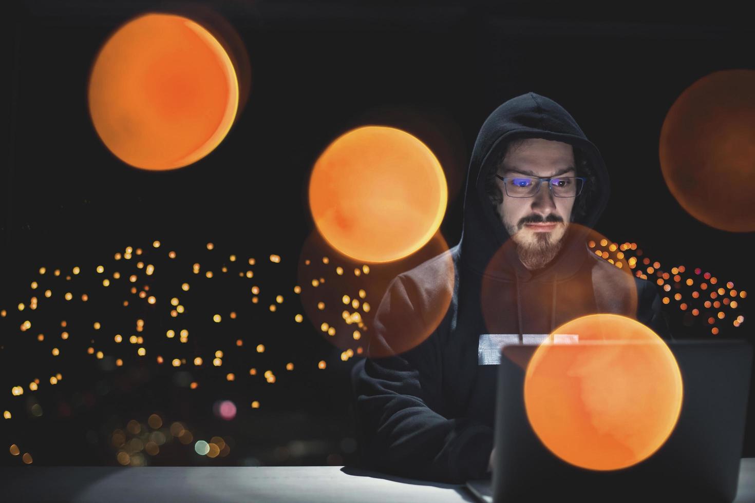 hacker using laptop computer while working in dark office photo