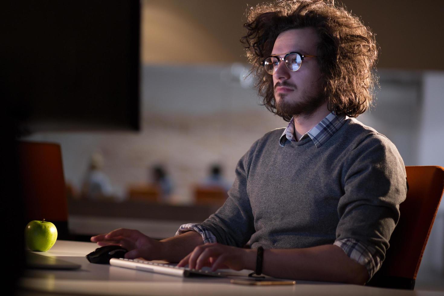 man working on computer in dark office photo