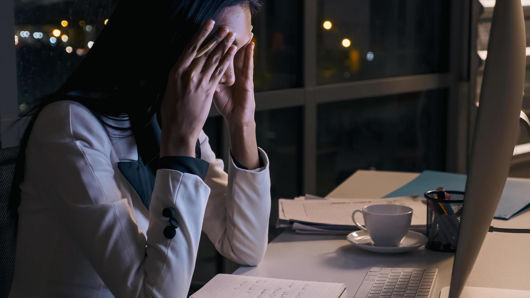 Stressed young Asian businesswoman working overtime at the office. photo