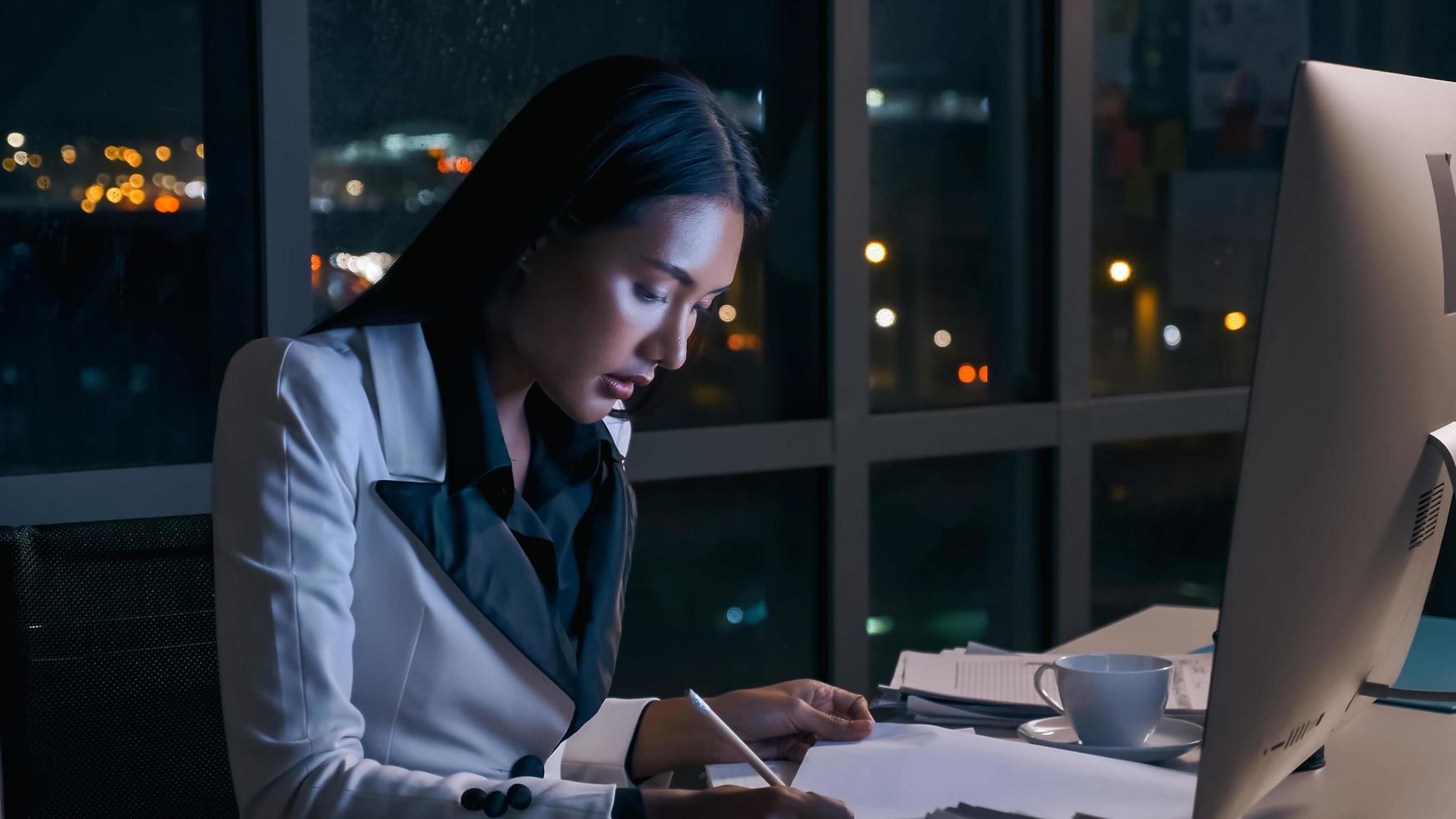 A young businesswoman concentrating on an analysis of work projects in office until late at night. photo